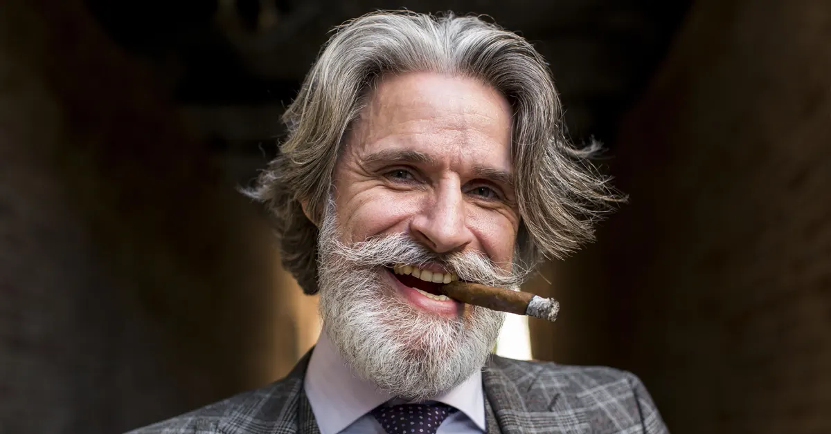 Starší elegantný muž s horiacou cigarou v ústach